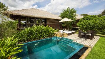 A poolside area with a thatched-roof structure, lounge chairs, and a wooden deck.