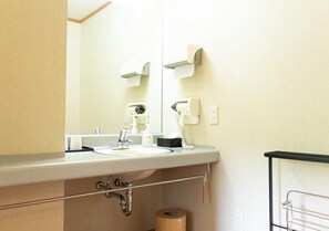 A bathroom with a sink, mirror, towel dispenser, and toilet paper. - Uematsuya Ryokan (Ueda)