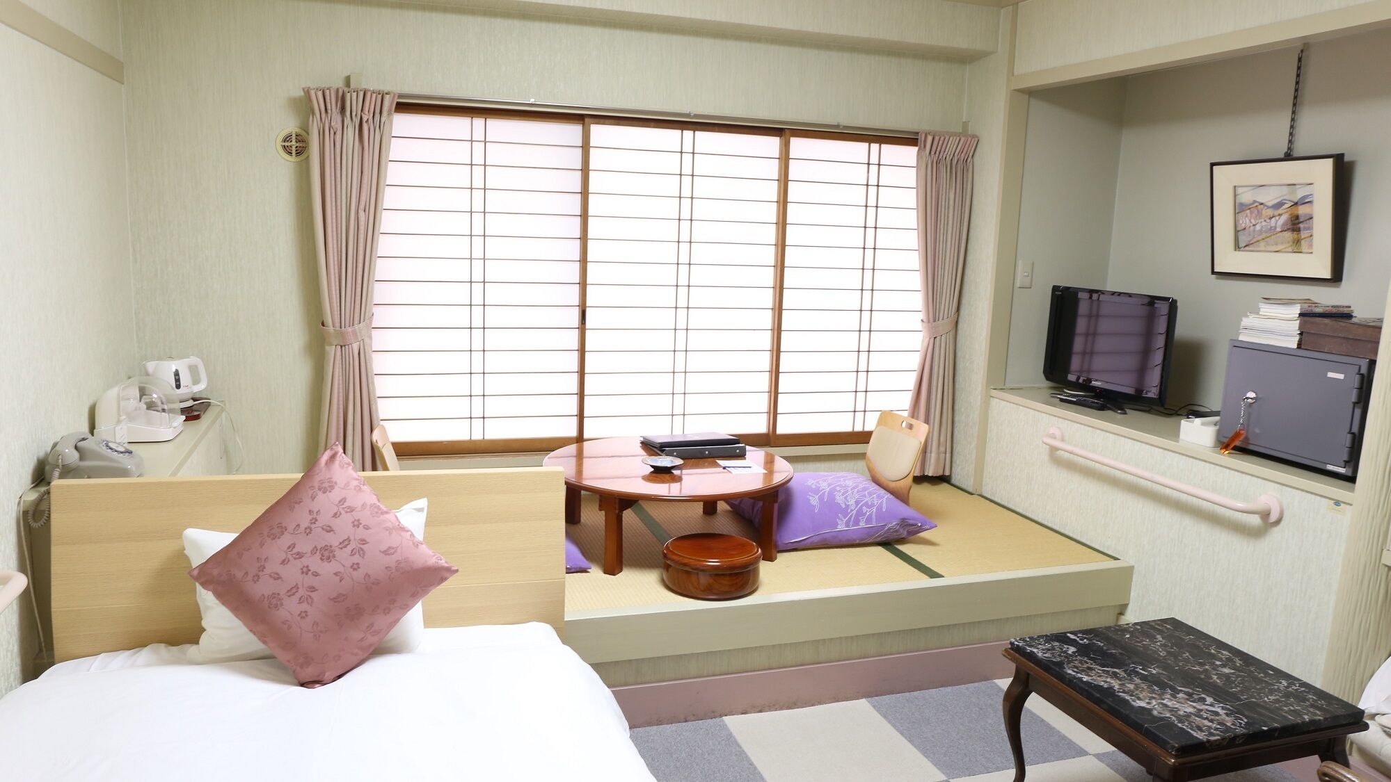 A room with a bed, a small table, a chair, a television, and a cabinet.