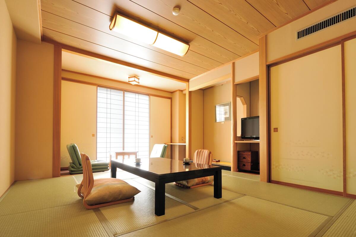 A traditional Japanese room with tatami flooring, a low table, and sliding doors.