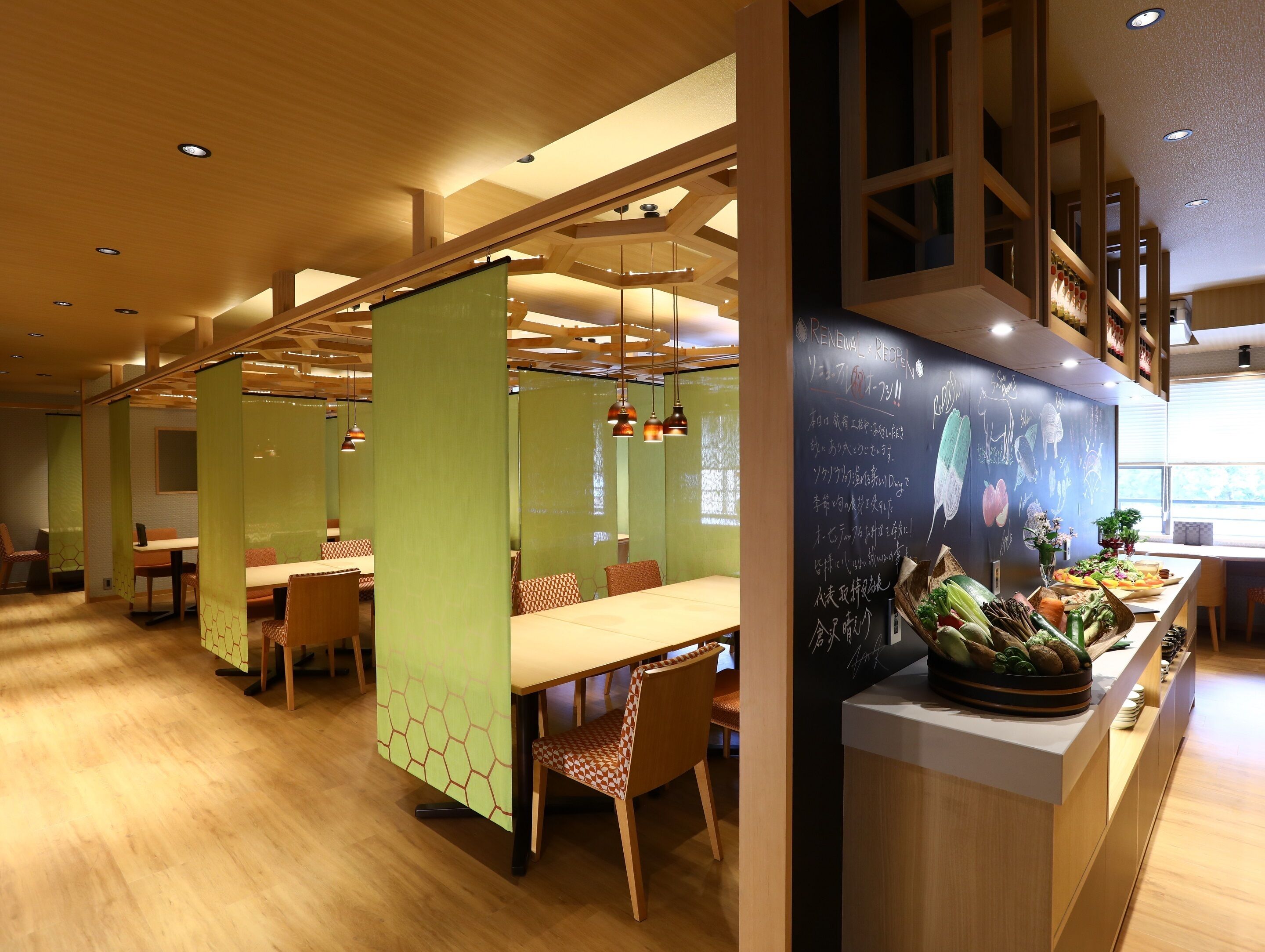 A restaurant with wooden flooring, green partition walls, and a chalkboard menu.