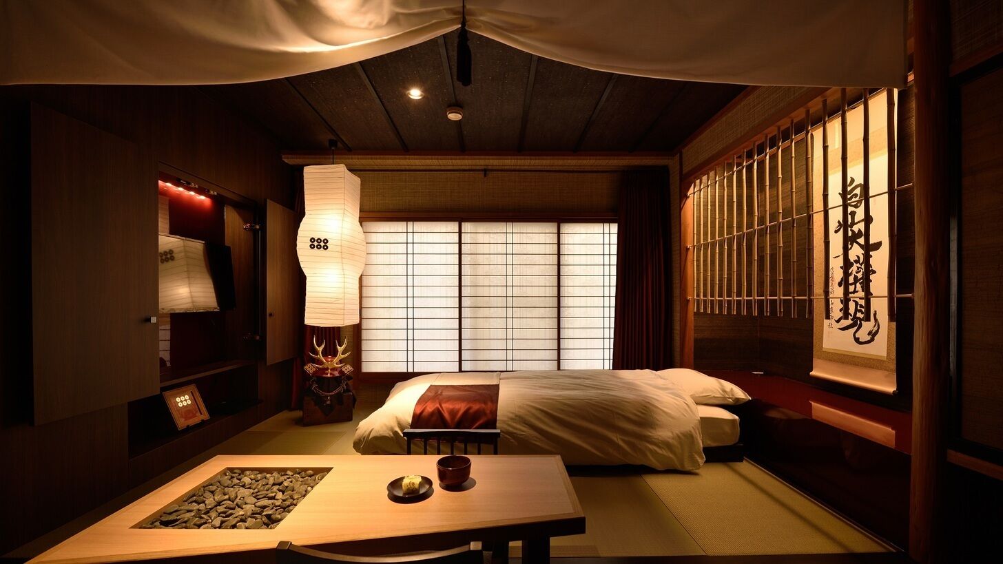 A traditional Japanese room with tatami flooring, a low table with a bowl and a plate, a bed with white bedding, and a shoji screen with calligraphy.