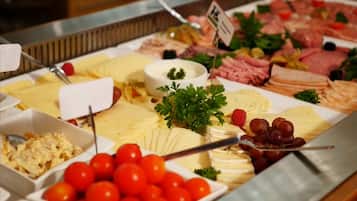 A buffet with various food items including cheeses, meats, and fruits.