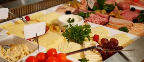 Un bufé con diversos alimentos, incluyendo quesos, carnes y frutas.