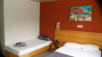 A hotel room with two beds, a wooden headboard, a nightstand, a telephone, and a painting on the wall.