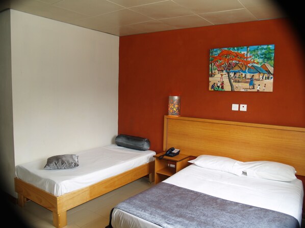 A hotel room with two beds, a wooden headboard, a nightstand, a telephone, and a painting on the wall. - Le Champ de Mars B&B (Port Louis)