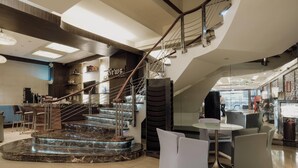 A modern interior with a marble staircase, a bar area, and seating arrangements. - Ramada by Wyndham Manila Central (Manila)
