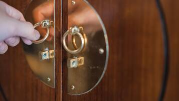 A hand holding a key, inserting it into a brass door handle.