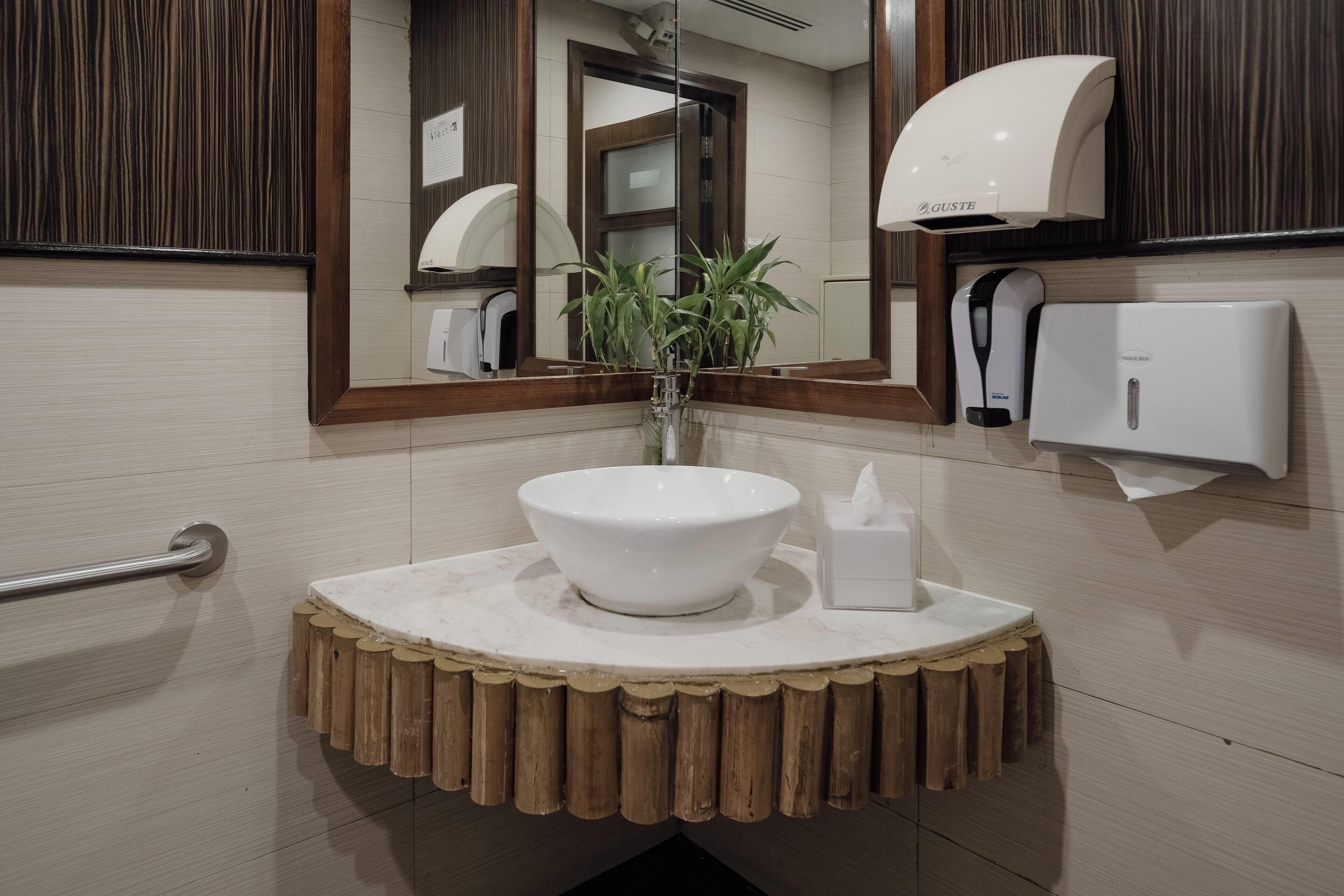 A bathroom with a white sink, a mirror, a towel dispenser, and a hand dryer.