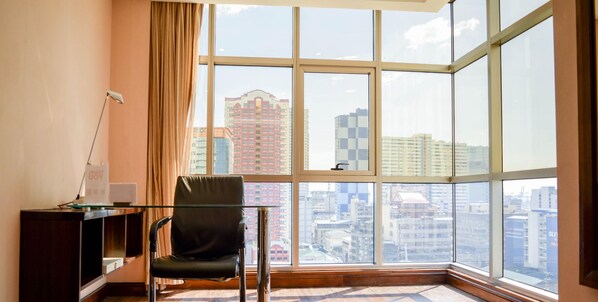 A modern room with a large window, a glass table, and a black chair.