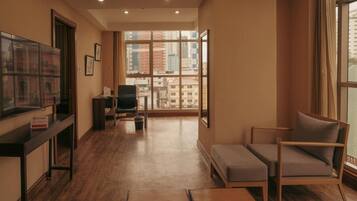 A modern living room with a large window, a sofa, a small table, and a television.
