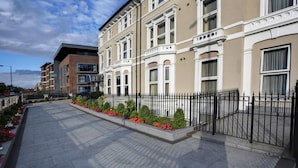 A row of townhouses with a paved walkway and a black metal fence. - Best Western London Highbury (London)