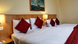 A hotel room with two beds, red and white bedding, a wooden headboard, a painting of a ship on the wall, and a nightstand with a bottle of water and a pen. - Best Western London Highbury (London)