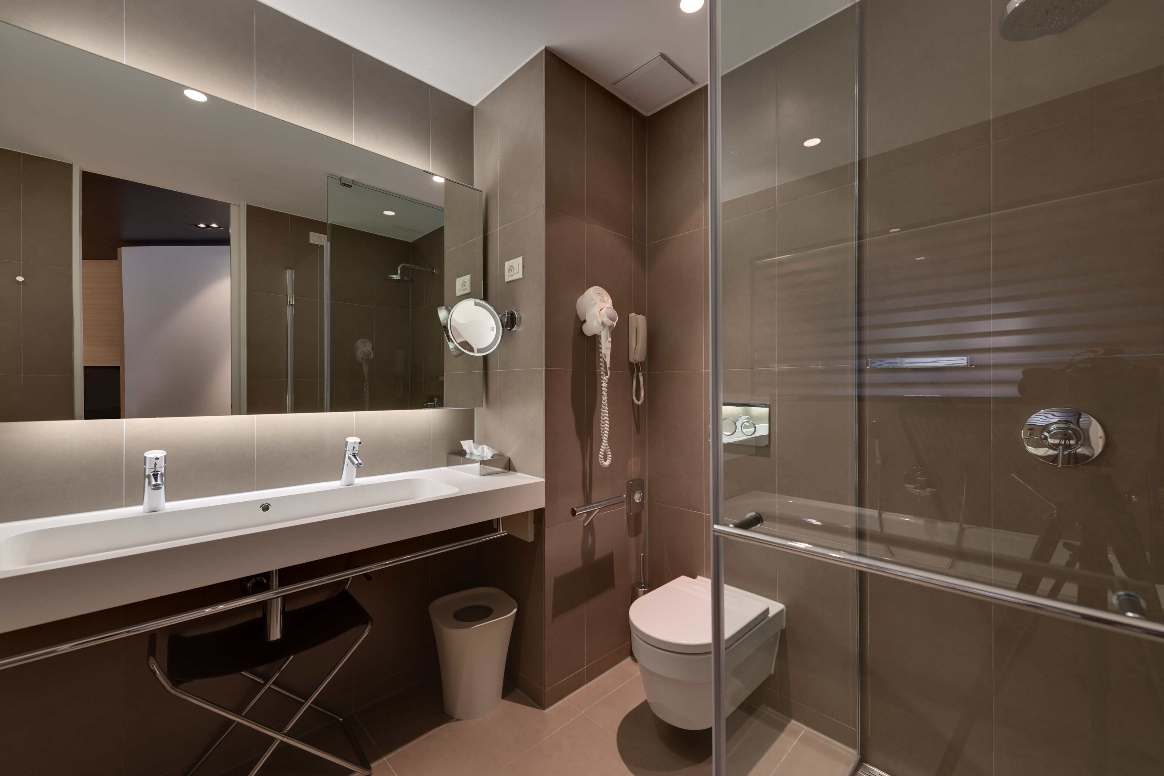 Un baño moderno con cabina de ducha de vidrio, un lavabo con espejo y un inodoro.