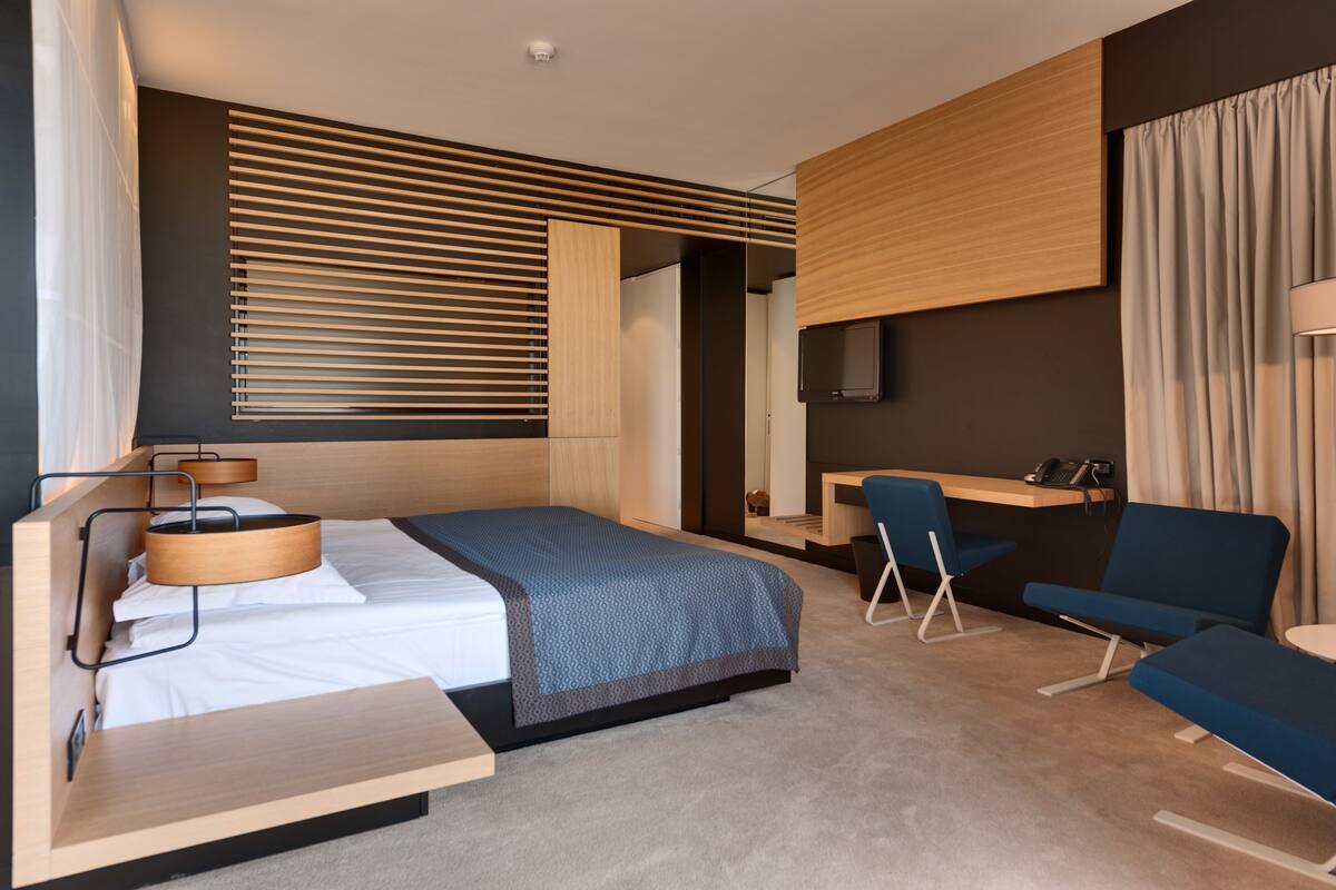 Una habitación de hotel moderna con cama, escritorio y zona de estar.