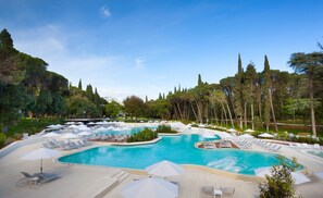 A large outdoor swimming pool surrounded by lounge chairs and umbrellas, with trees and a clear sky in the background. - Lone Hotel by Maistra Collection (Rovinj)
