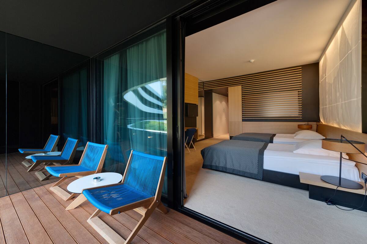 Una habitación de hotel con una cama grande, un escritorio pequeño y un área de estar con sillas azules y una mesa.