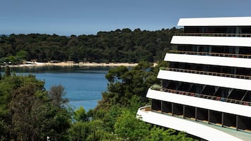 Un edificio moderno con varios balcones con vistas a un lago y zona boscosa.
