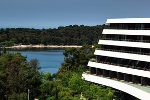 A modern building with multiple balconies overlooking a lake and forested area. - Lone Hotel by Maistra Collection (Rovinj)