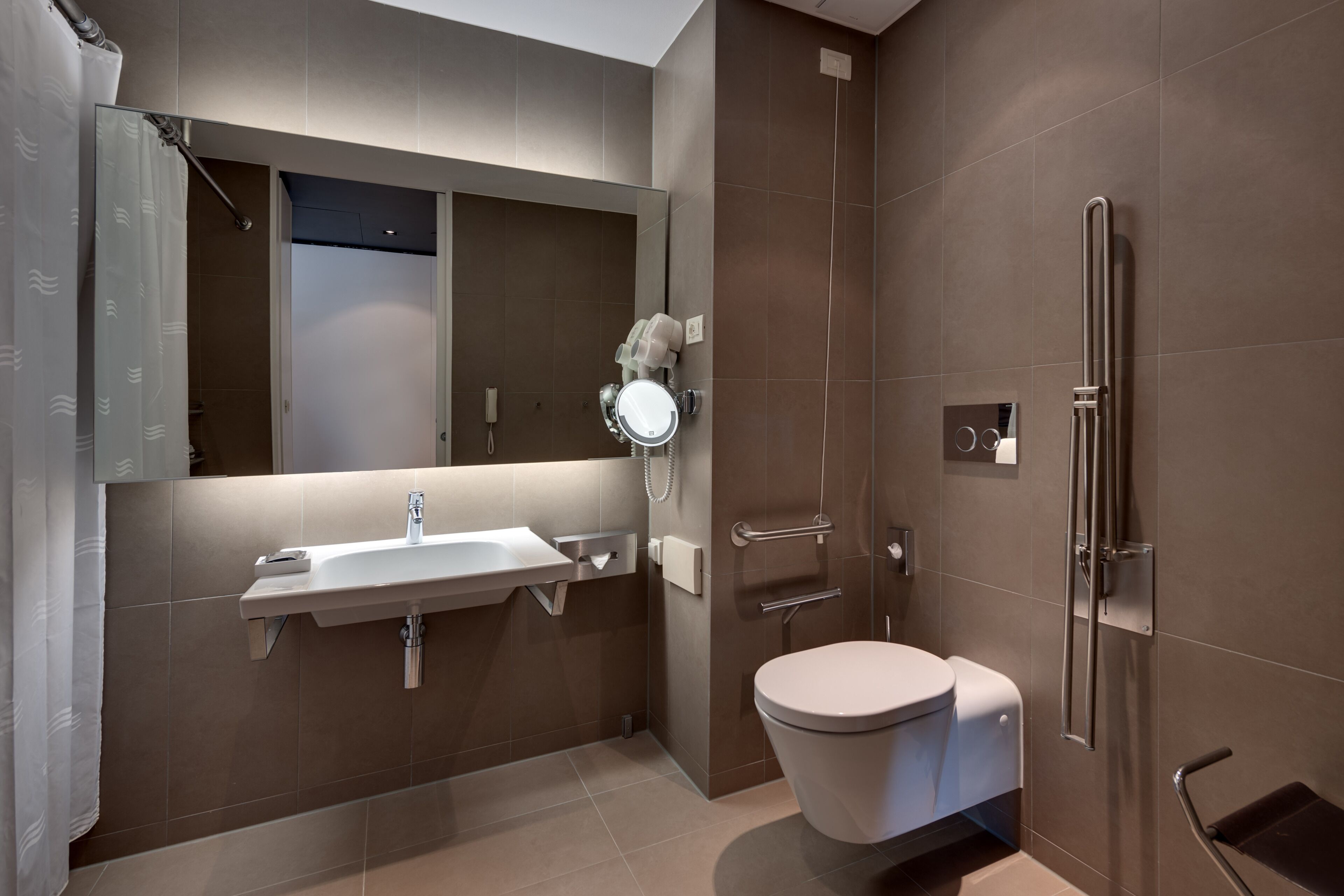 A modern bathroom with a sink, mirror, toilet, and shower.