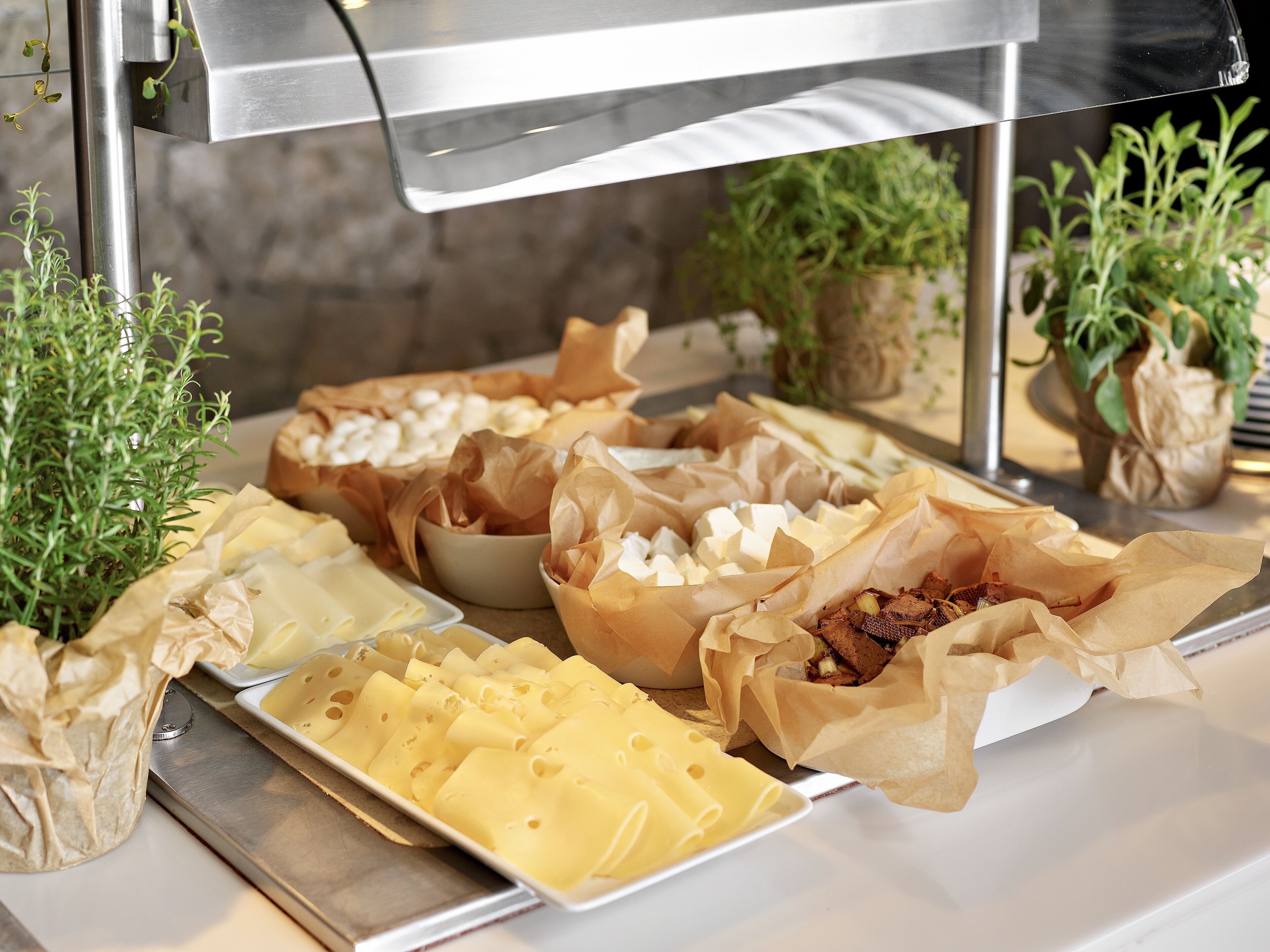 A buffet with various cheeses, meats, and pastries.