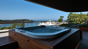 Un jacuzzi en una terraza de madera con vistas al mar y barcos.