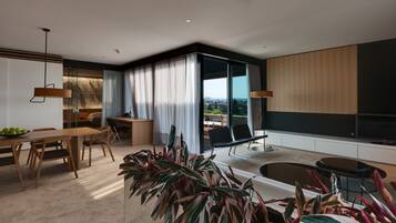 A modern living room with a dining area, large windows, and a view of the city.