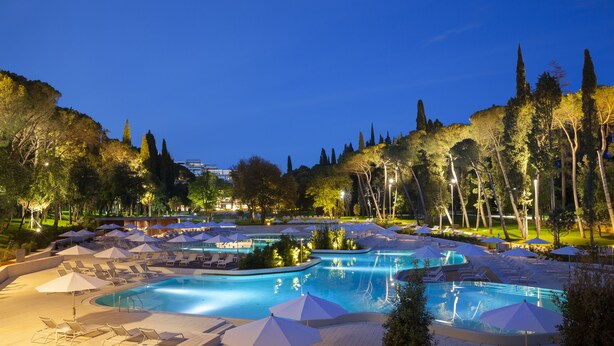 Un resort con varias piscinas, sillas de descanso y sombrillas.