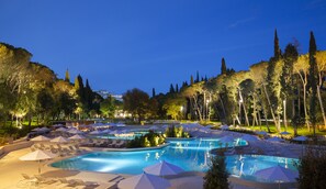 Un resort con varias piscinas, sillas de descanso y sombrillas.