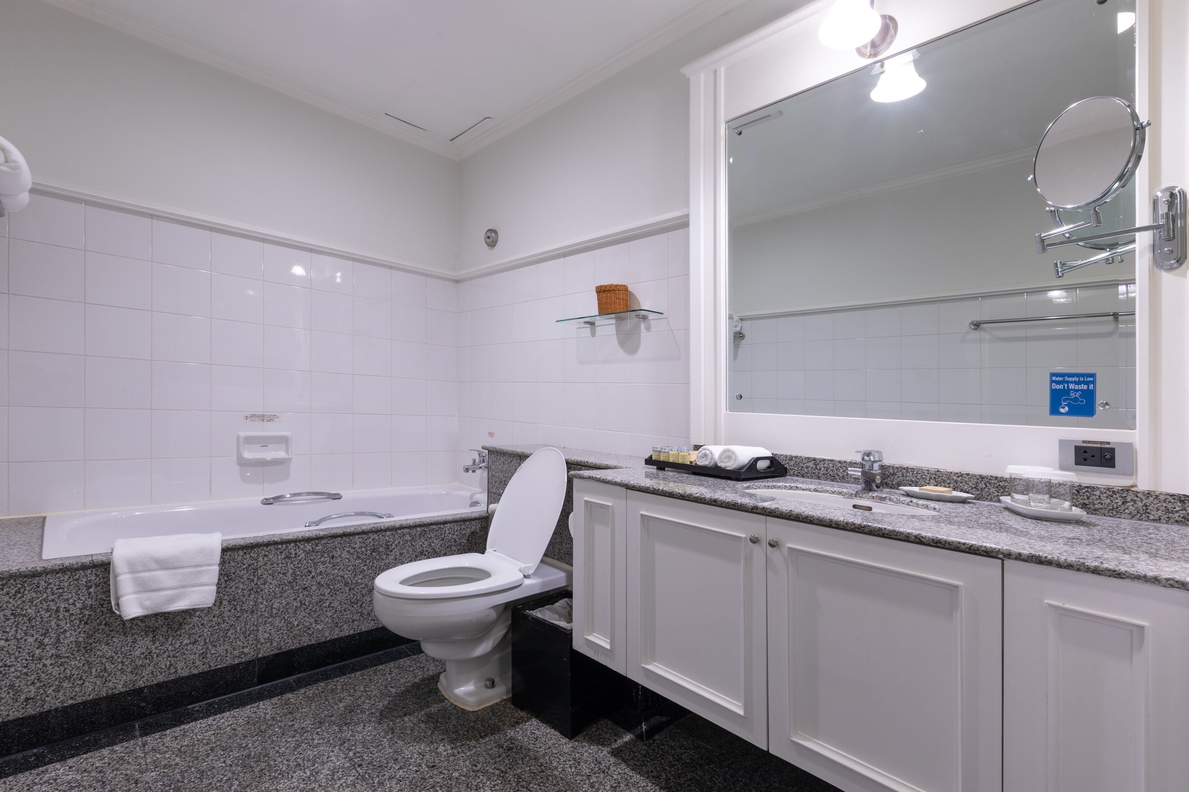 Un baño moderno con inodoro blanco, una bañera y un espejo grande.