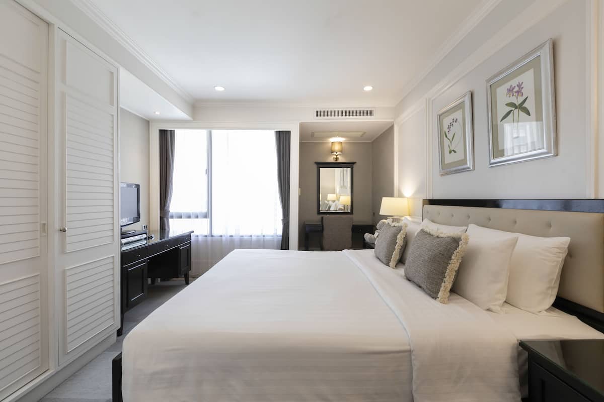 Een hotelkamer met een groot bed, een bureau met een televisie, een spiegel en kunstwerken in een lijst aan de muur.