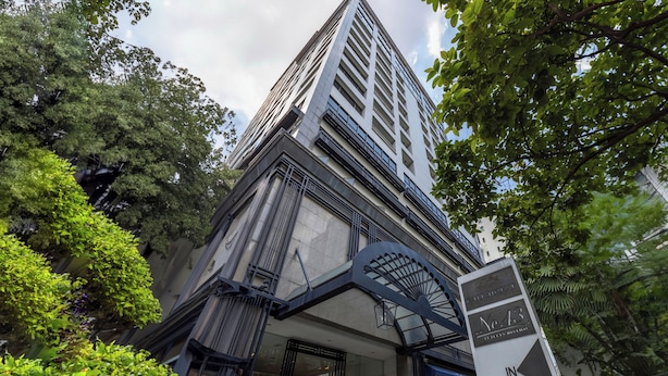 Une entrée d’hôtel moderne, dotée d’un auvent imposant, d’une enseigne indiquant le numéro de chambre 43, et d’une végétation luxuriante qui entoure le bâtiment.