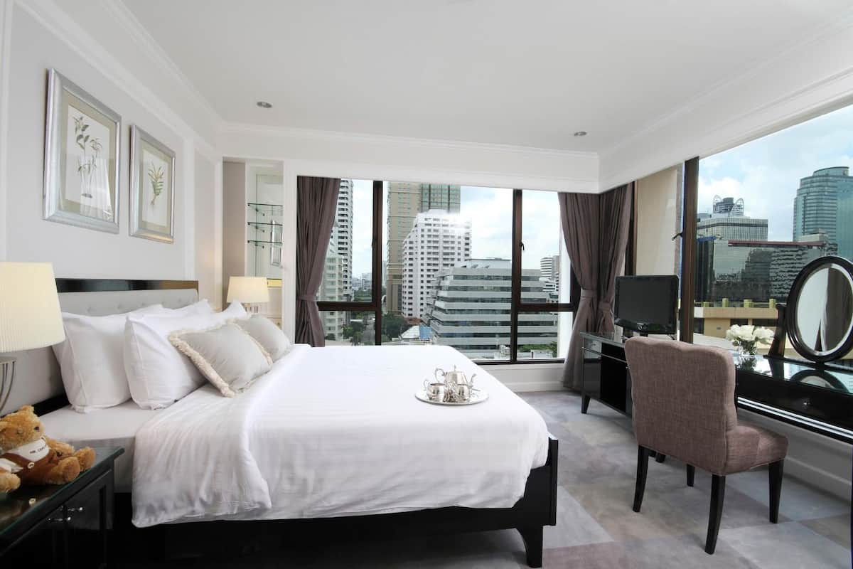 Een hotelkamer met een groot bed, een bureau, een stoel en uitzicht op de stad.