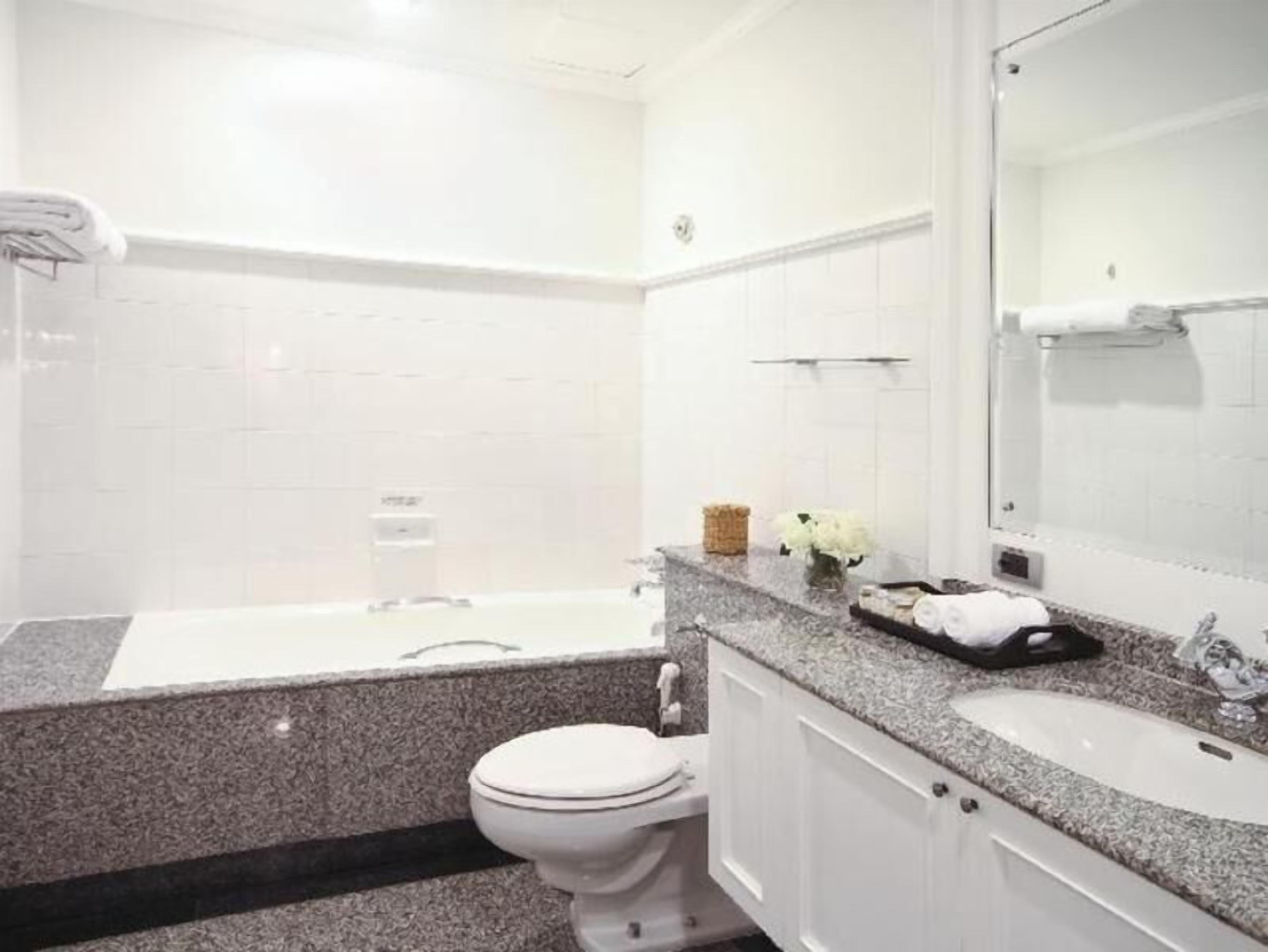 A bathroom with a white toilet, a bathtub, a sink, and a mirror.