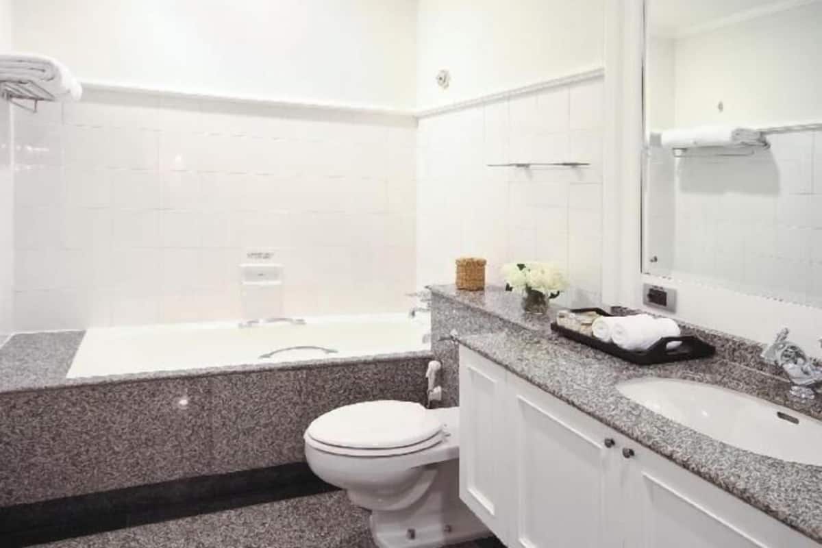 Een badkamer met een wit toilet, een badkuip, een wastafel en een spiegel.