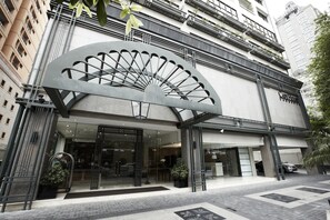 A modern hotel entrance with a large fan-like structure, glass doors, and a parking area. - Cape House Hotel, Bangkok (Bangkok)