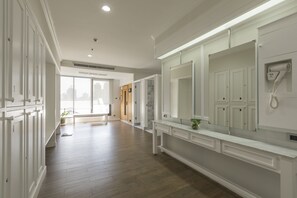 A spacious hallway with wooden flooring, white cabinetry, and a large mirror. - Cape House Hotel, Bangkok (Bangkok)