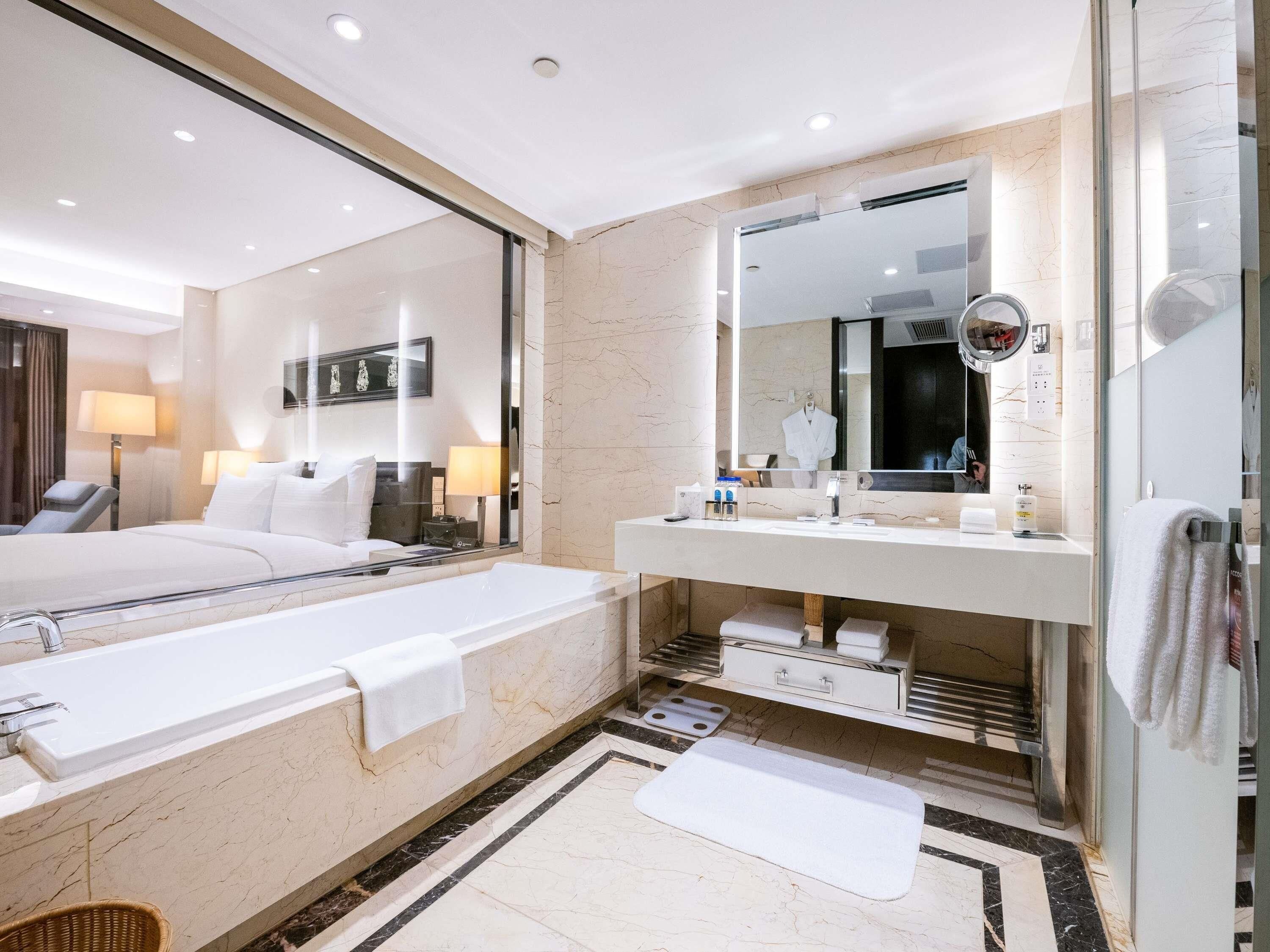 Un baño de hotel moderno con una bañera grande, un tocador con espejo y una zona de ducha separada.