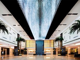 A spacious lobby with a high ceiling, a central column, and a reception desk.