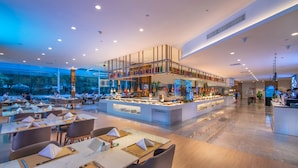 En moderne restaurant med et centralt barområde, flere spiseborde og udsigt til det fri.