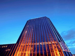 Un edificio alto y moderno con fachada de vidrio reflectante y un diseño vertical destacado.