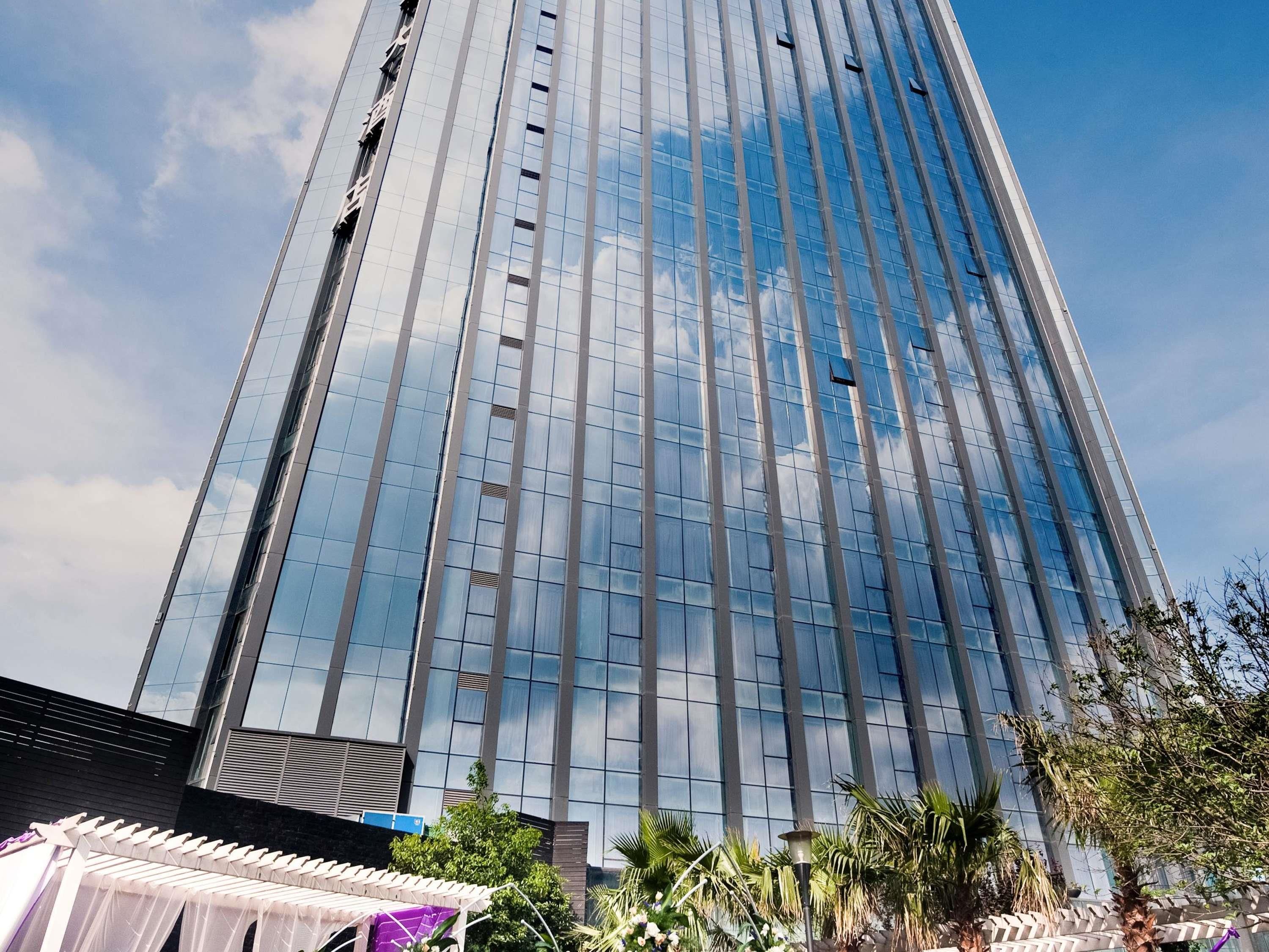 Un edificio alto y moderno con ventanas de vidrio reflectante y un cielo despejado.
