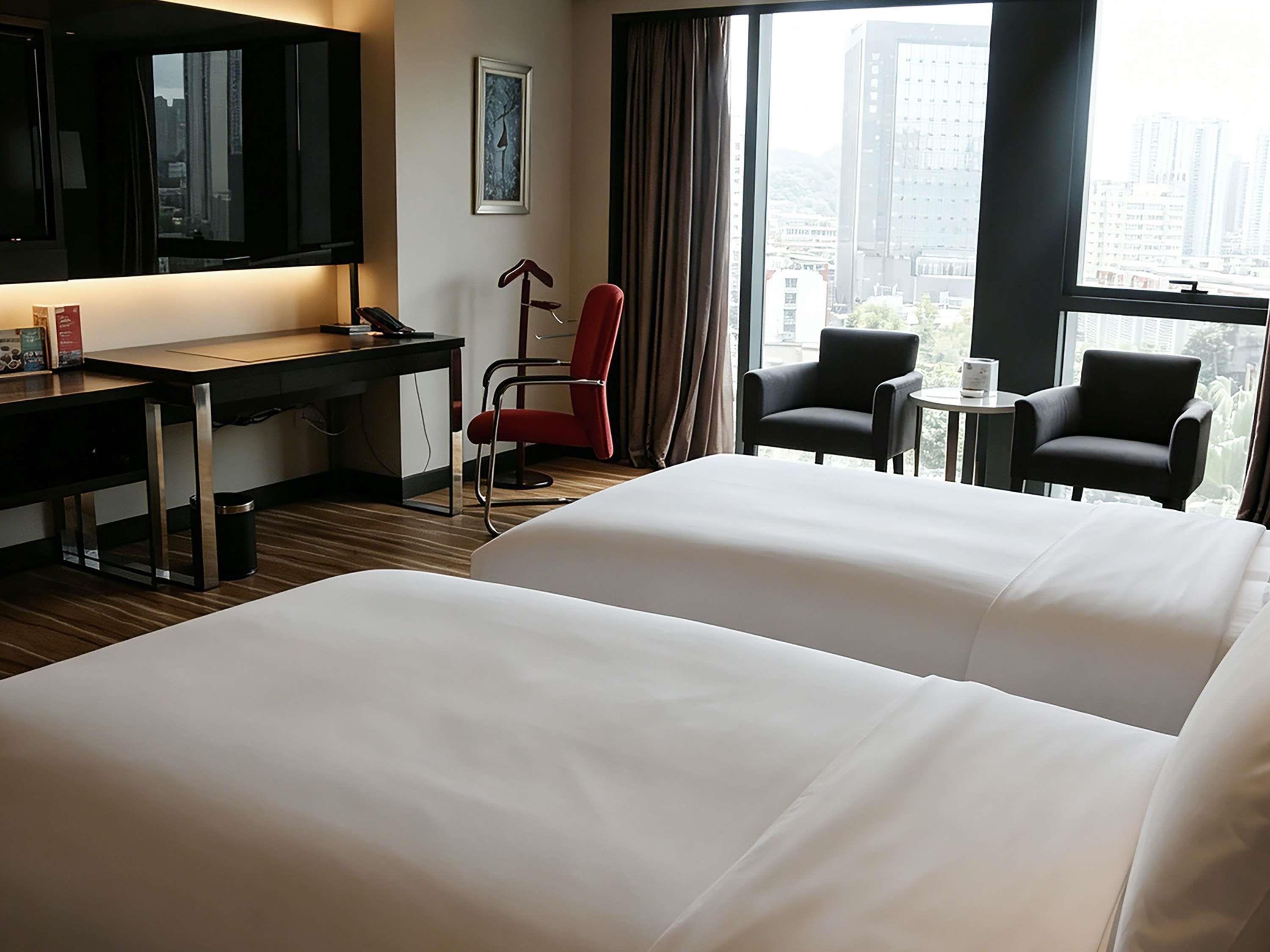 Habitación de hotel con dos camas, un escritorio, una silla y un televisor.