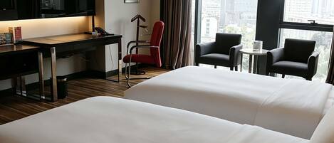 Habitación de hotel con dos camas, un escritorio, una silla y un televisor.