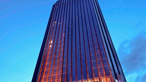 En høj, moderne skyskraber med en spejlgrund facade og et markant skilt øverst.