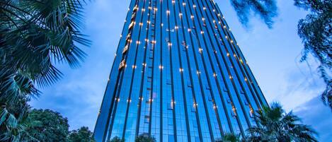 A tall, modern hotel with a glass facade and numerous windows.