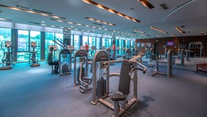 Une salle de sport moderne dotée de divers appareils d’entraînement, de grandes fenêtres et d’un aménagement spacieux.