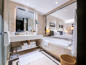A modern bathroom with a large mirror, dual sinks, a bathtub, and a shower area. - Pullman Guiyang (Guiyang)