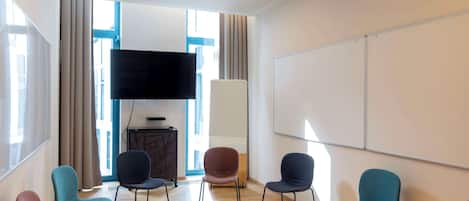 Un salón de conferencias con una gran televisión de pantalla plana, una pizarra y varias sillas.