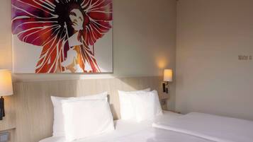 A hotel room with a large bed, two white pillows, a headboard, and two wall-mounted lamps.
